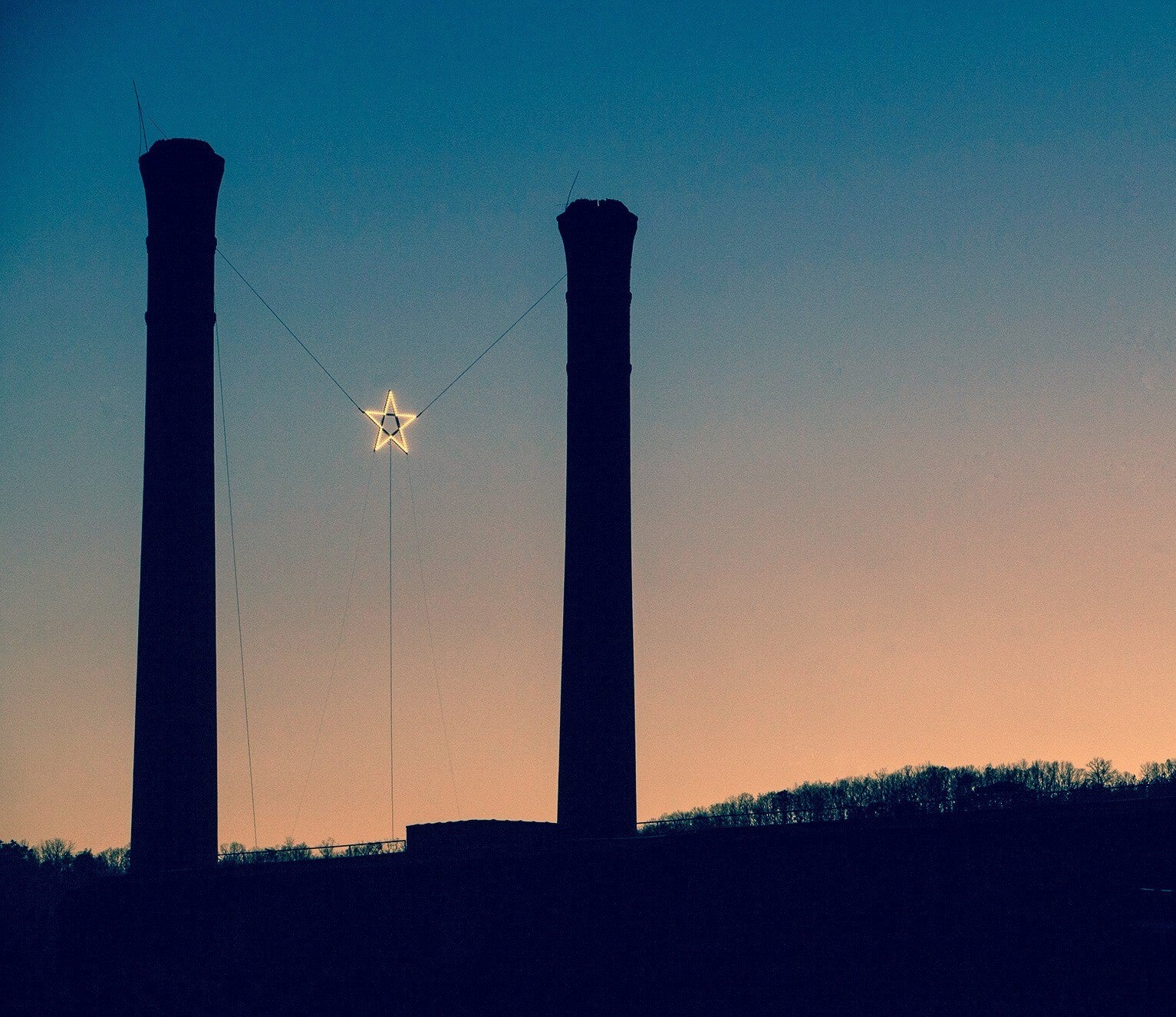 Lindale star hanging between two large smokestacks at sunrise Lindale star hanging between two large smokestacks at sunrise